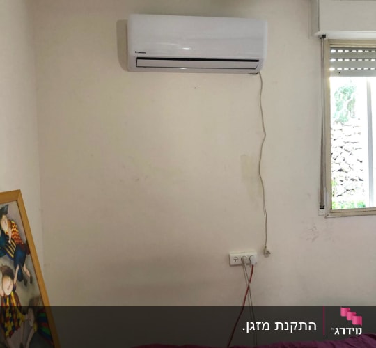 מזגן מותקן על קיר לבן בחדר שינה